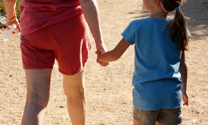 a photo of an adult and child walking together shown from the back