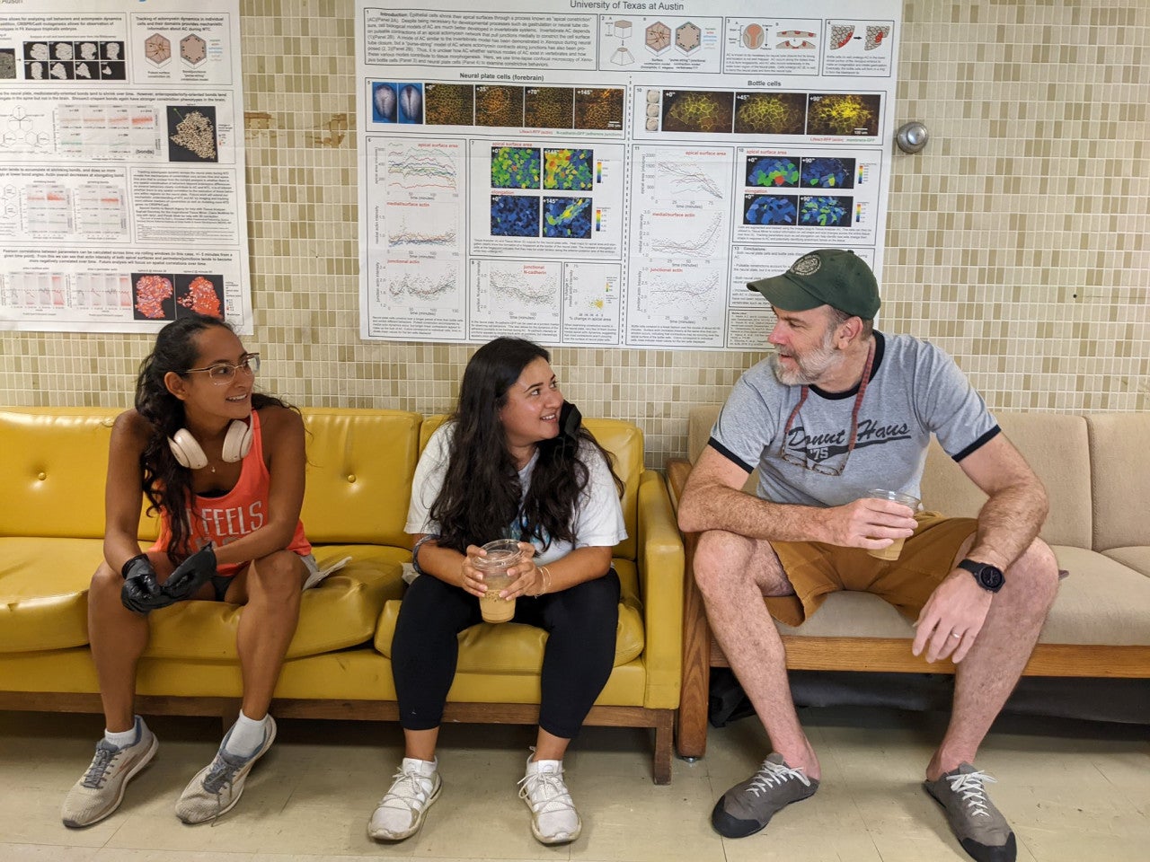 Two undergraduate students sit on a couch next to developmental biologist John Wallingford