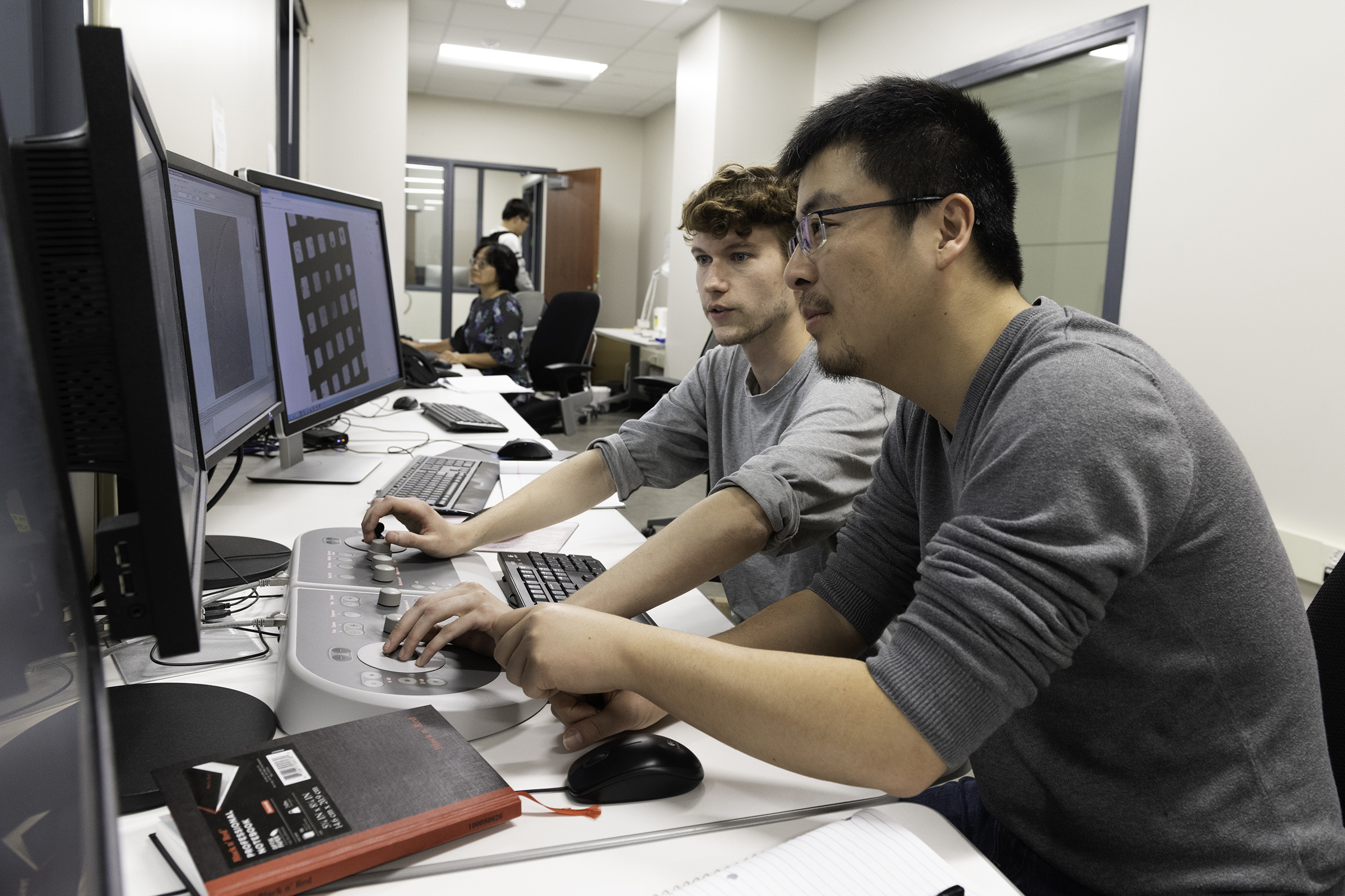 Two students, Nianshuang Wang and Daniel Wrapp, look at data on a computer screen